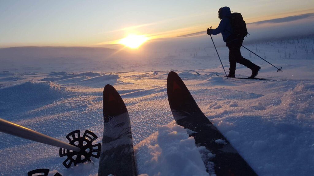Seikkailija hiihtämässä Åsnes tunturisuksilla lumisessa tunturimaisemassa.